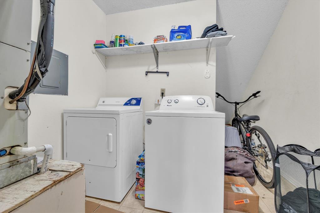 Laundry room featuring light tile patterned flooring, electric panel, separate washer and dryer, heating unit, and a textured ceiling