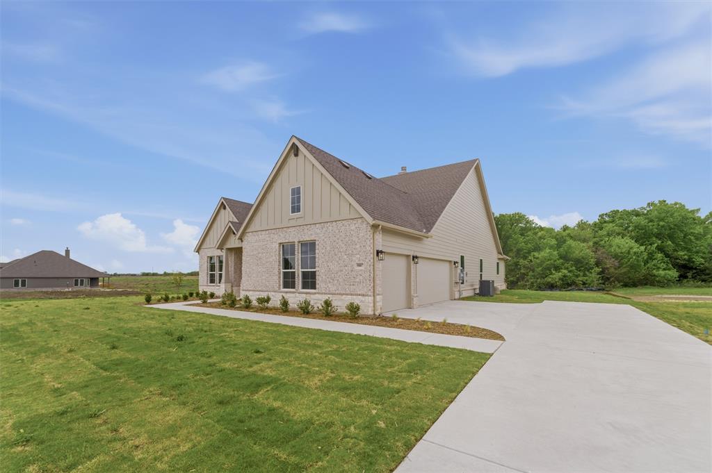 View of property exterior with board and batten siding, brick siding, a lawn, and concrete driveway