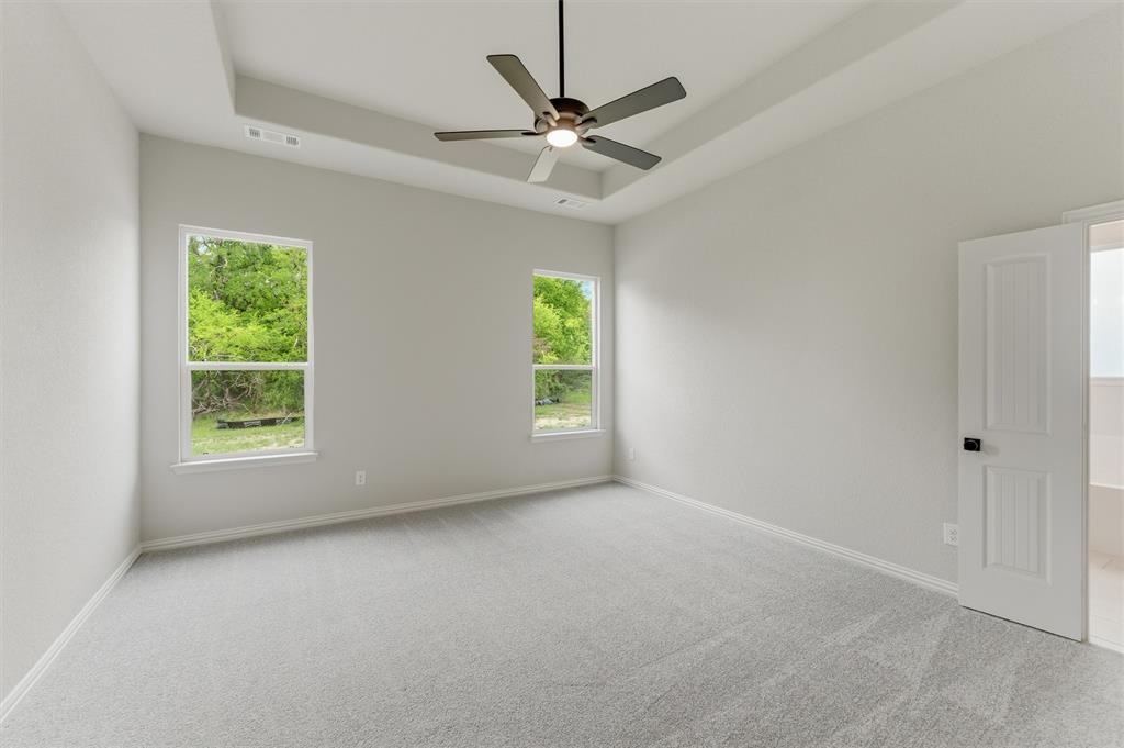 Unfurnished room featuring light carpet, a tray ceiling, and ceiling fan