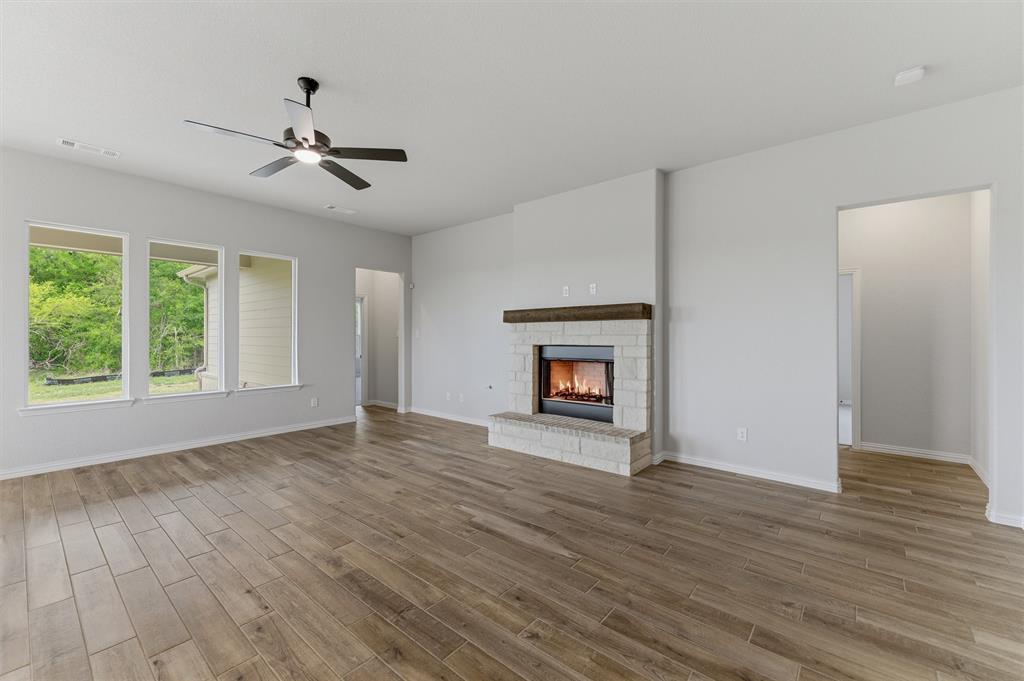 Unfurnished living room featuring a ceiling fan, a fireplace, and light wood-style floors