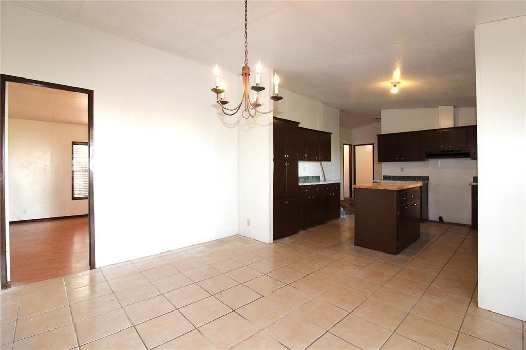 Kitchen with dark brown cabinets, a chandelier, hanging light fixtures, a center island, and light tile patterned floors Kitchen with dark brown cabinets, a chandelier, hanging light fixtures, a center island, and light tile patterned floors