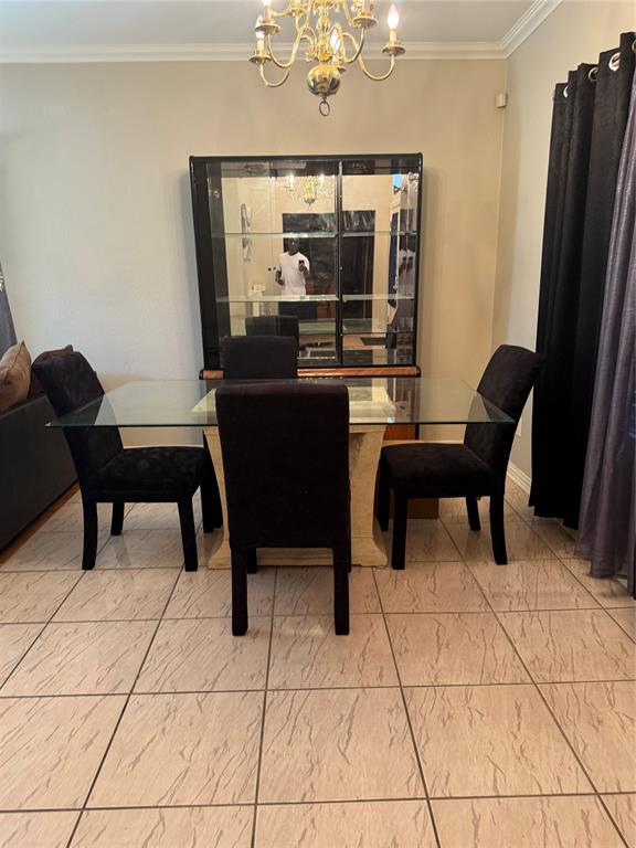 Dining area with crown molding, a chandelier, and tile patterned floors