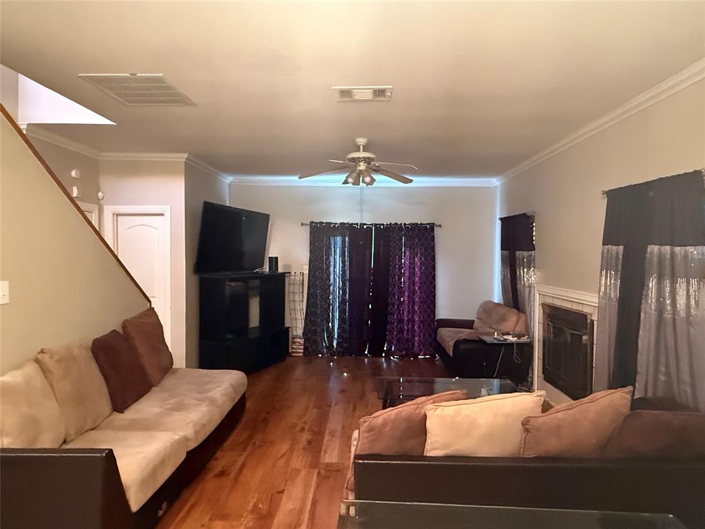 Living area with ceiling fan, crown molding, wood finished floors, and a tile fireplace