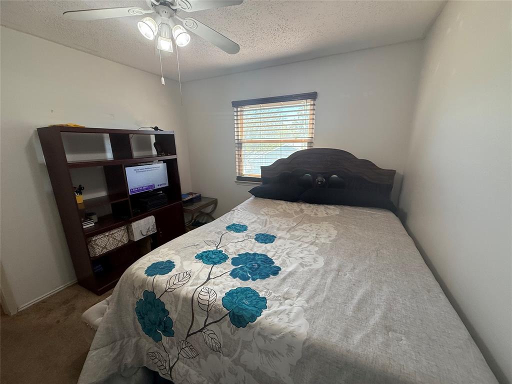 Bedroom featuring a textured ceiling, carpet flooring, and ceiling fan