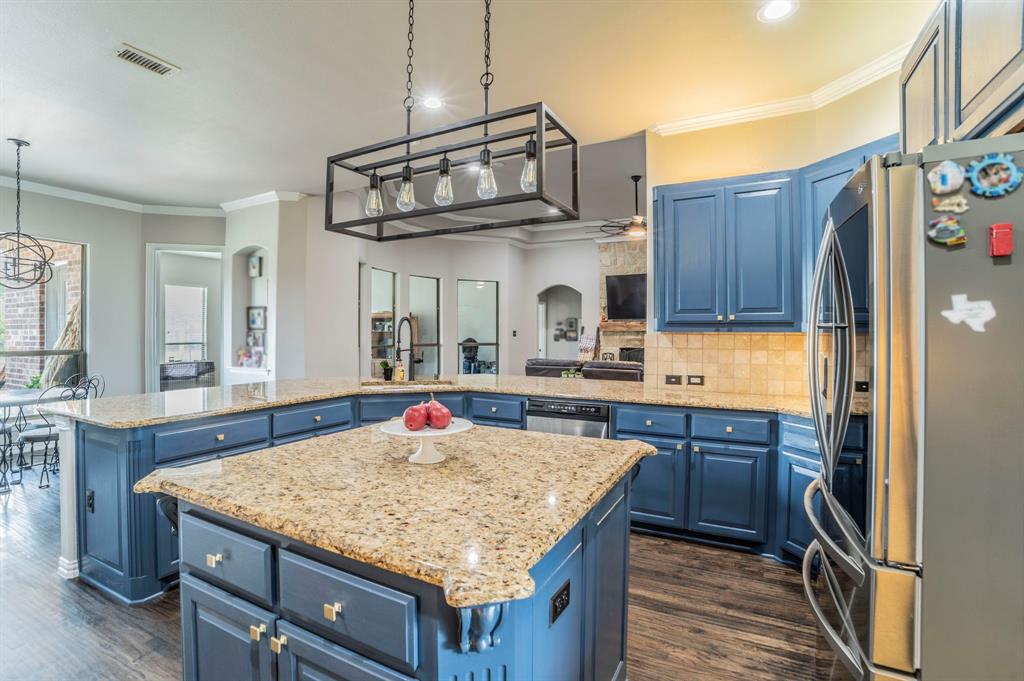 Kitchen featuring ornamental molding, blue cabinetry, stainless steel appliances, backsplash, and light stone countertops
