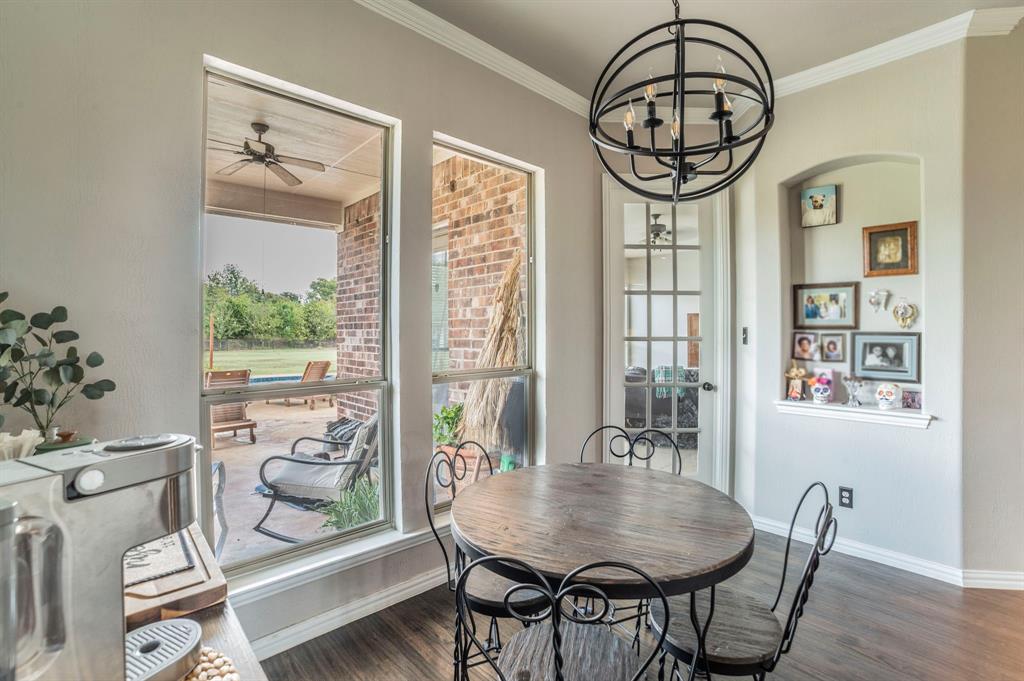 Dining space featuring plenty of natural light, dark wood finished floors, a ceiling fan, crown molding, and a chandelier