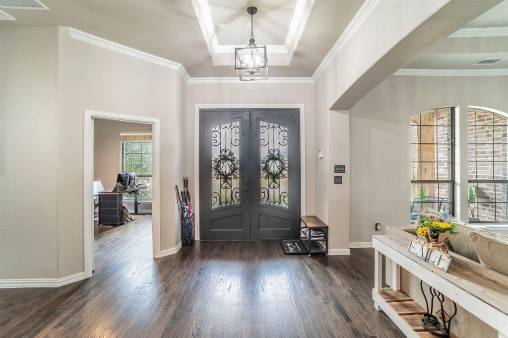 Foyer entrance featuring dark wood-style floors, ornamental molding, french doors, and a chandelier