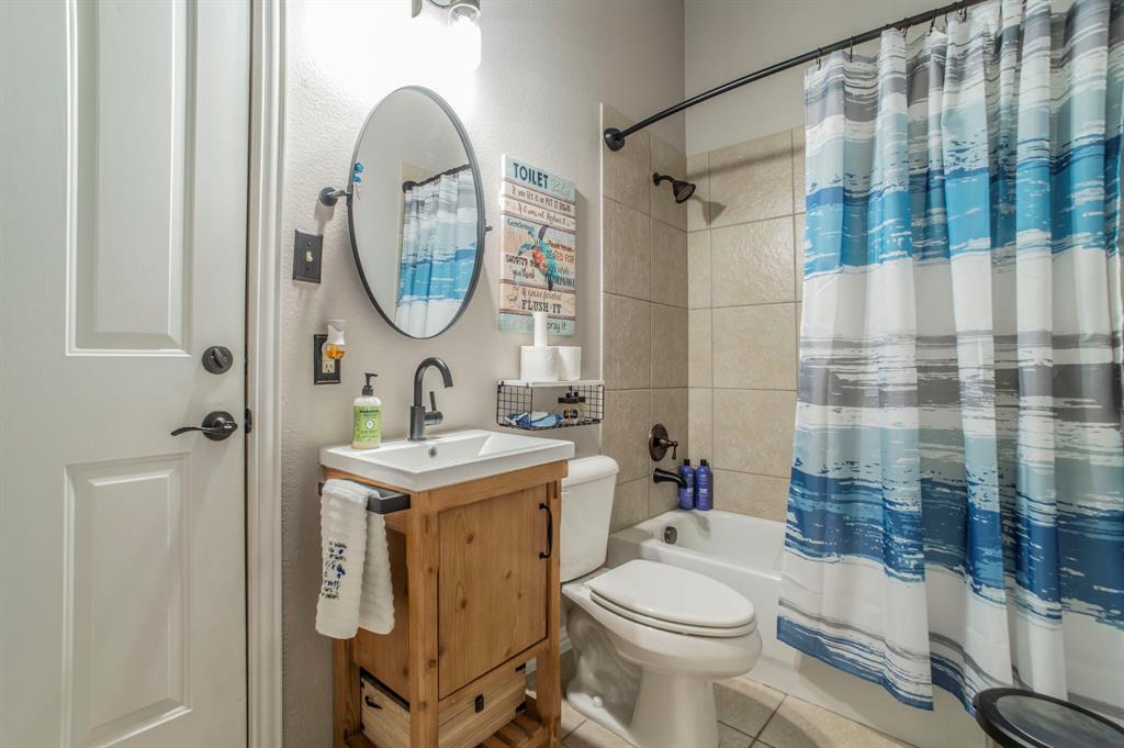 Full bathroom with tile patterned floors, shower / bath combination with curtain, vanity, and a textured wall
