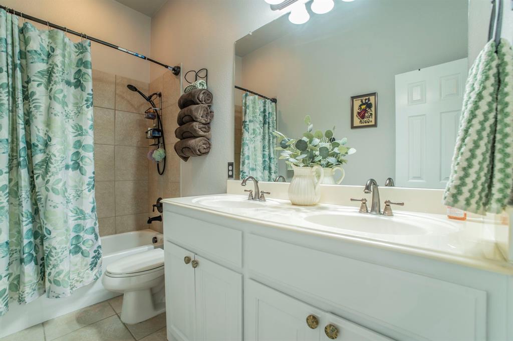 Full bathroom featuring shower / bath combo, double vanity, and light tile patterned floors
