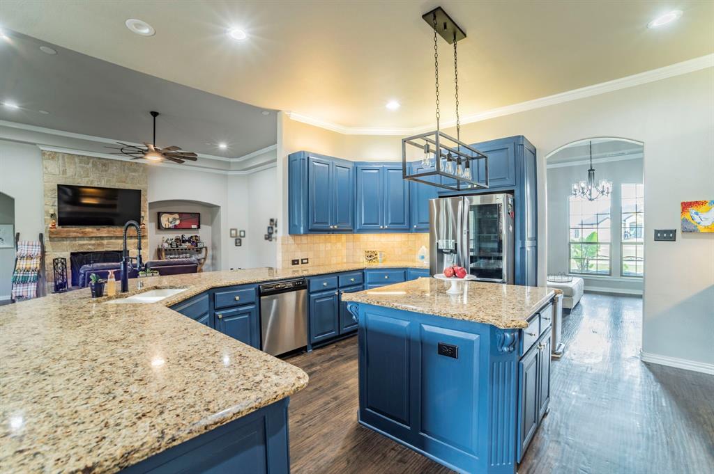 Kitchen featuring arched walkways, blue cabinets, backsplash, crown molding, and open floor plan