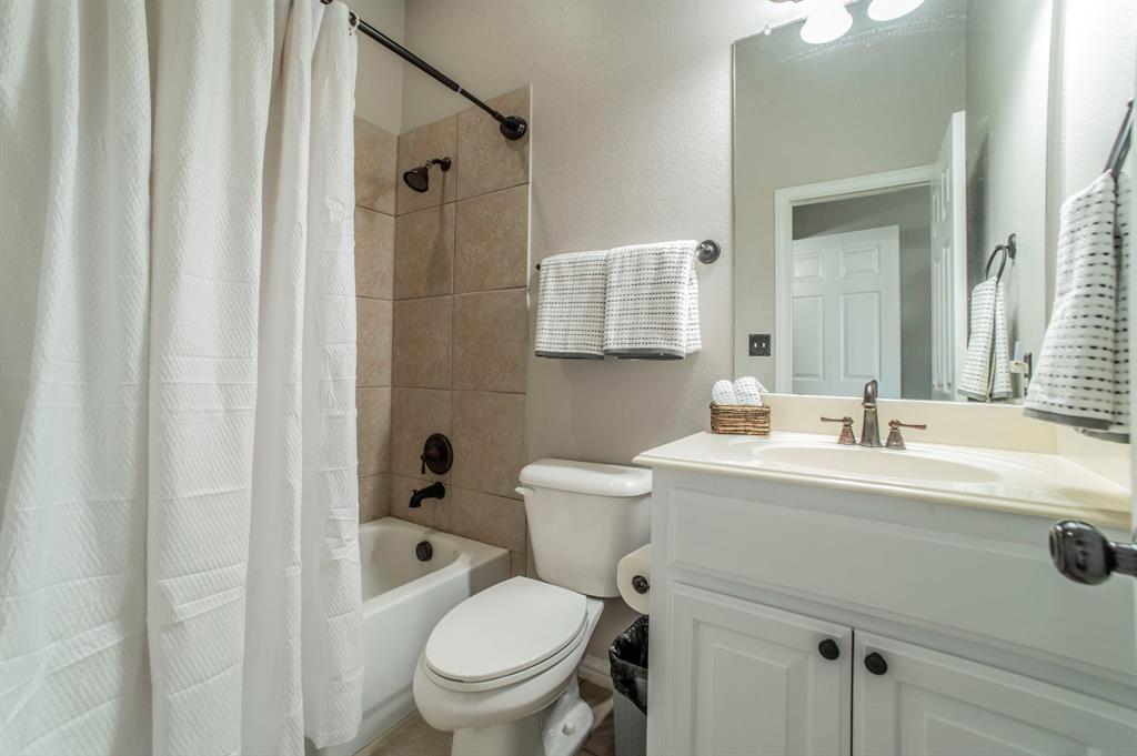 Full bath featuring shower / bathtub combination with curtain, vanity, and a textured wall
