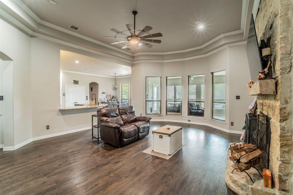 Living area featuring dark wood-style flooring, a ceiling fan, ornamental molding, a fireplace, and arched walkways