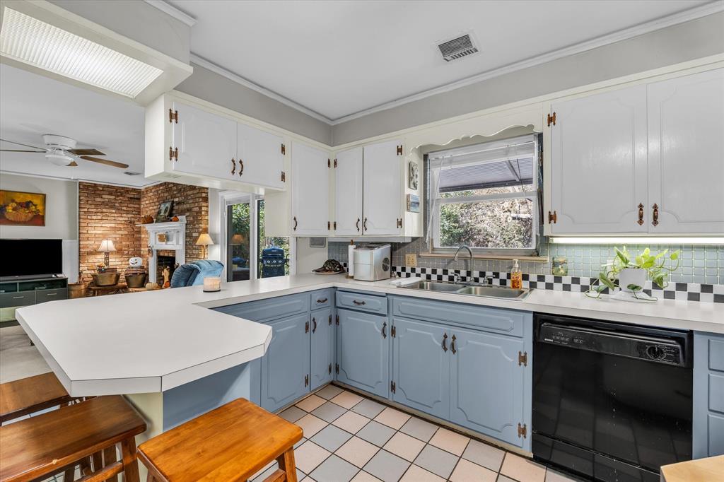 Kitchen featuring a peninsula, black dishwasher, light countertops, open floor plan, and a breakfast bar Kitchen featuring a peninsula, black dishwasher, light countertops, open floor plan, and a breakfast bar