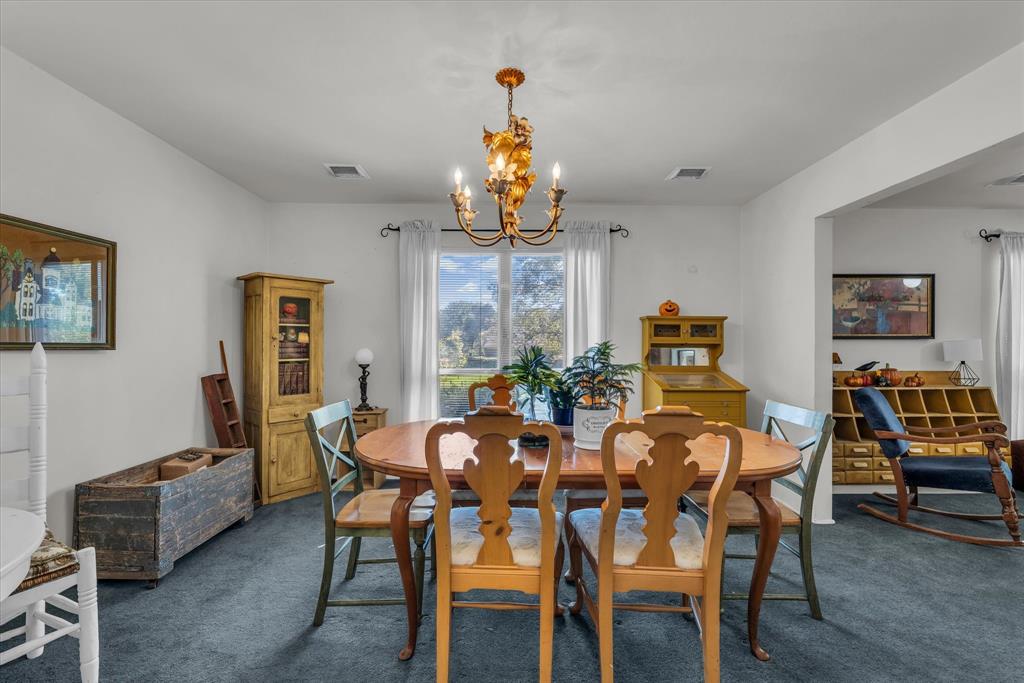 Dining room with dark colored carpet and a chandelier Dining room with dark colored carpet and a chandelier