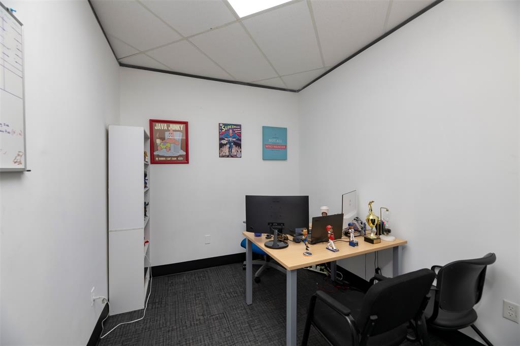 Home office with a drop ceiling and dark carpet