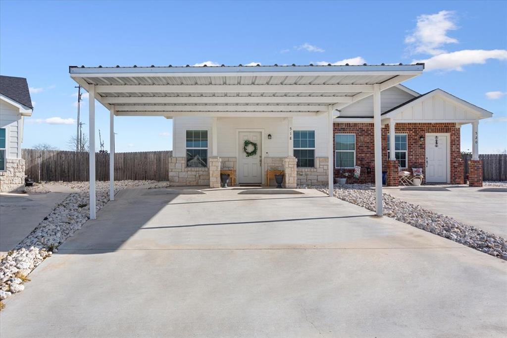 View of front facade with a carport, board and batten siding, and stone siding