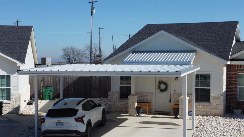 View of front of house featuring stone siding, a metal roof, a standing seam roof, and a shingled roof