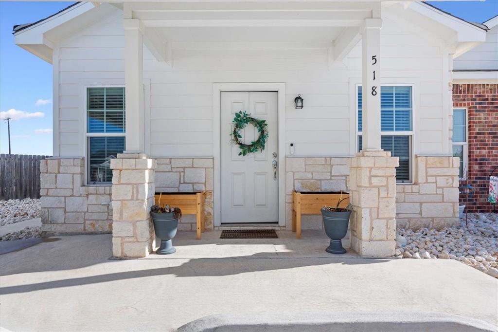View of exterior entry with stone siding and covered porch