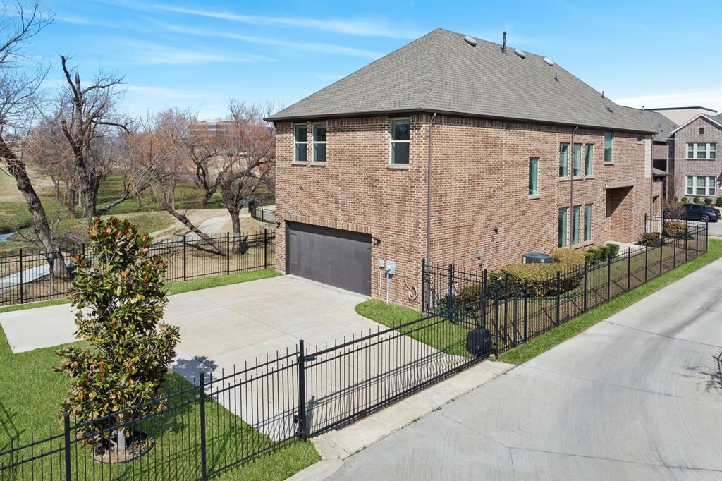 View of property exterior with a fenced front yard, brick siding, an attached garage, and driveway