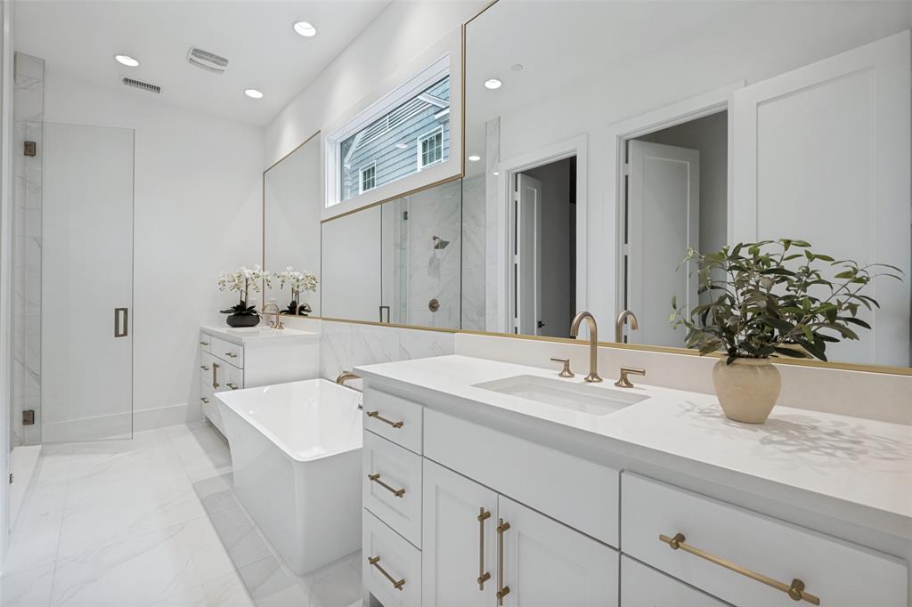 The relaxing primary bathroom features light tile finishes, a generous sized walk-in shower, and a separate soaking tub.