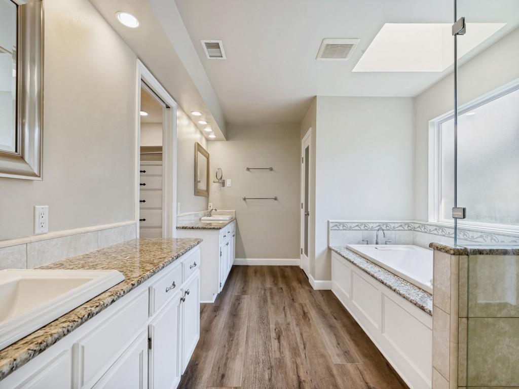 Primary Bathroom with vanity, a shower stall, a bath, and dark wood-type flooring