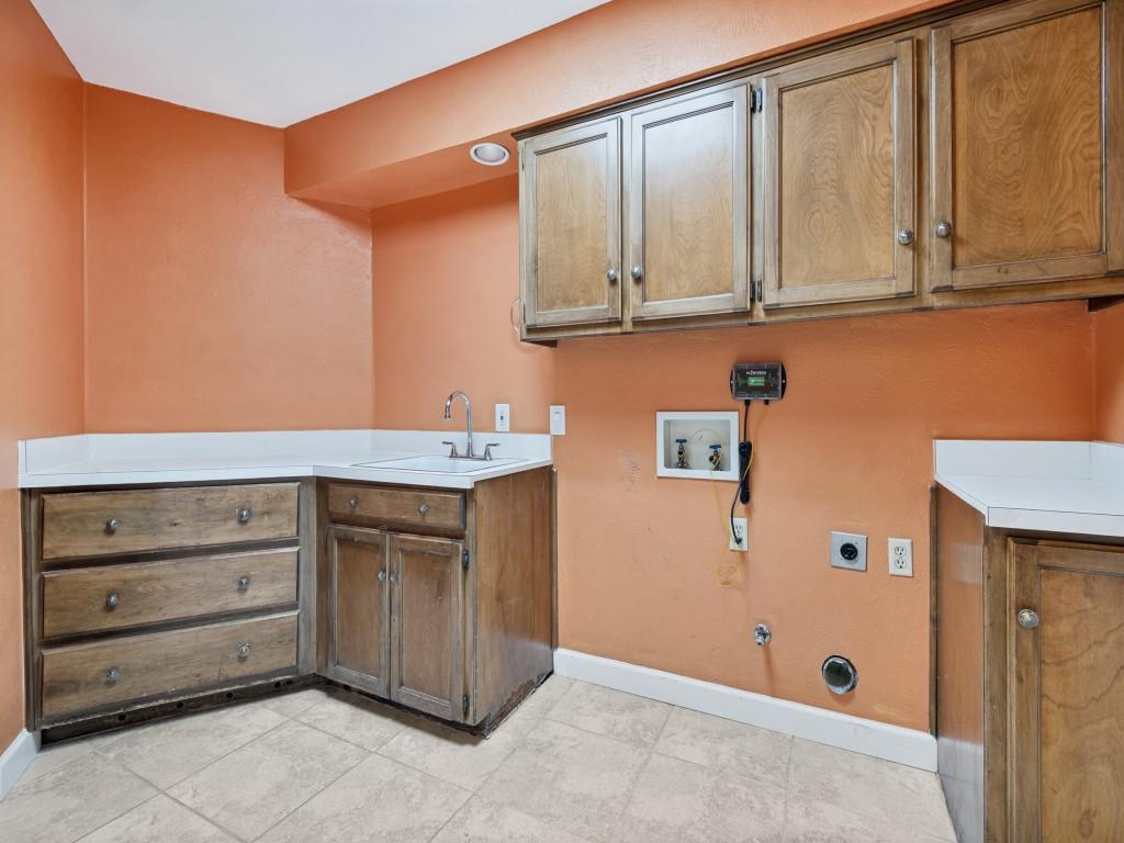 Laundry area - Full Size washer dryer area with skylight, cabinet space, and light tile patterned floors