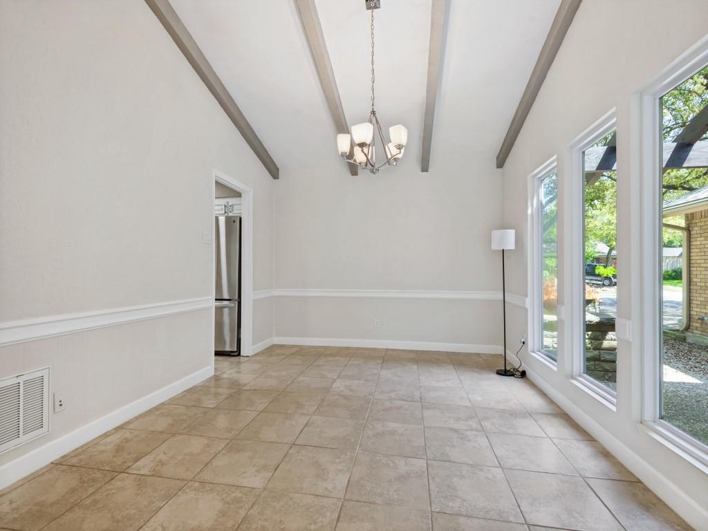Dining area with a chandelier, vaulted ceiling with beams, and light tile patterned floors
