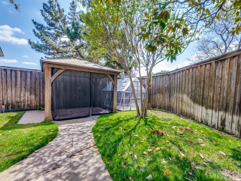 Fenced backyard featuring a gazebo and green house