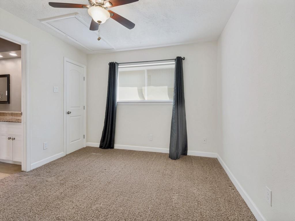 Secondary Bedroom with light carpet, ensuite bath, a ceiling fan, and a textured ceiling