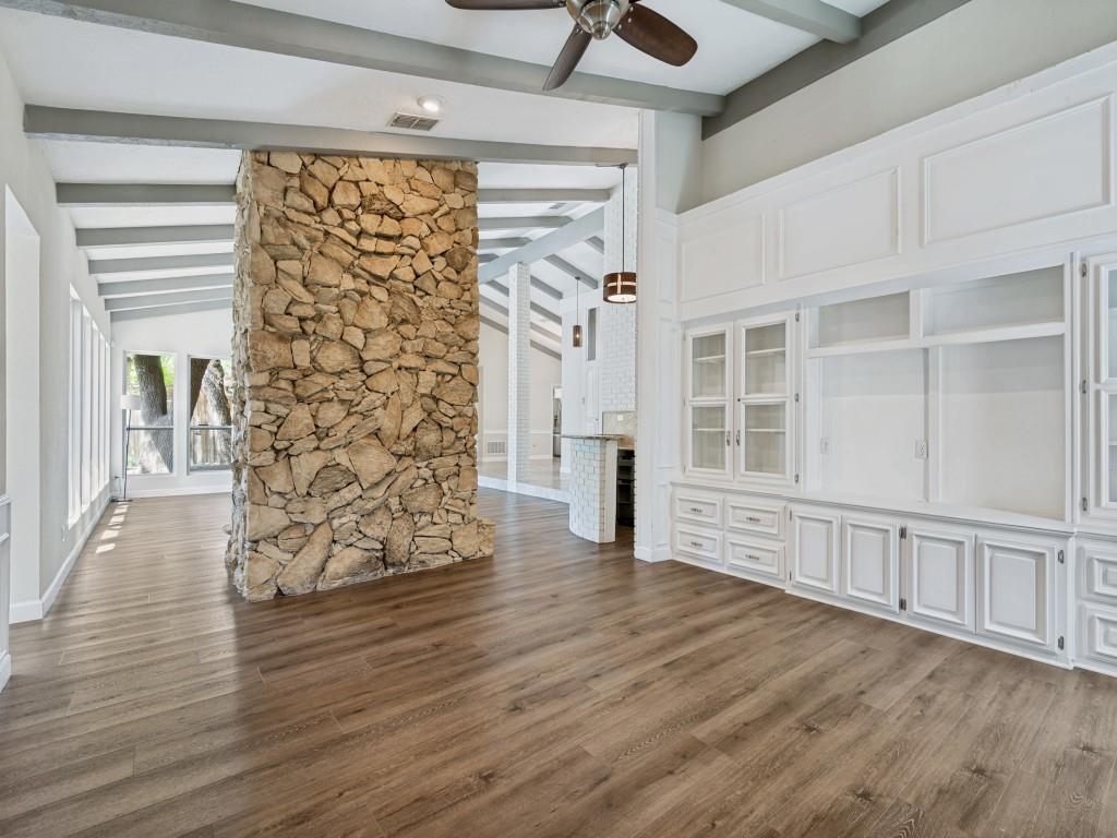 Living room with ceiling fan, dark wood-style floors, and vaulted ceiling with beams