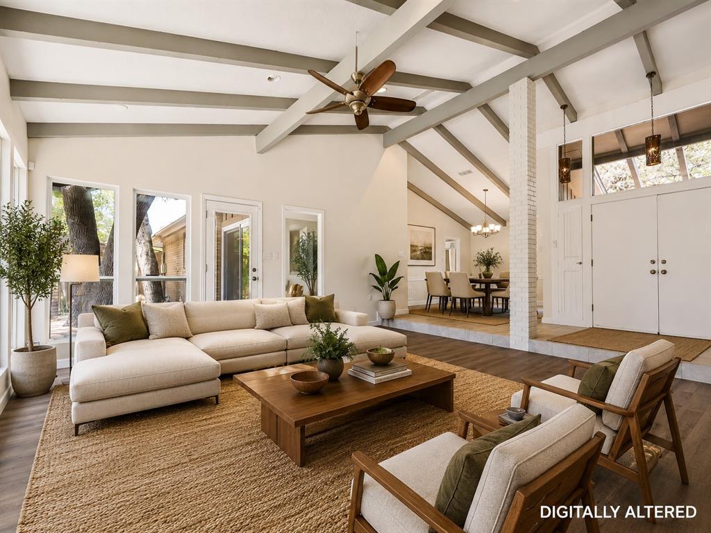 Spacious living area featuring a vaulted ceiling with exposed beams, wood-finish flooring, and multiple large windows - Virtual Staging