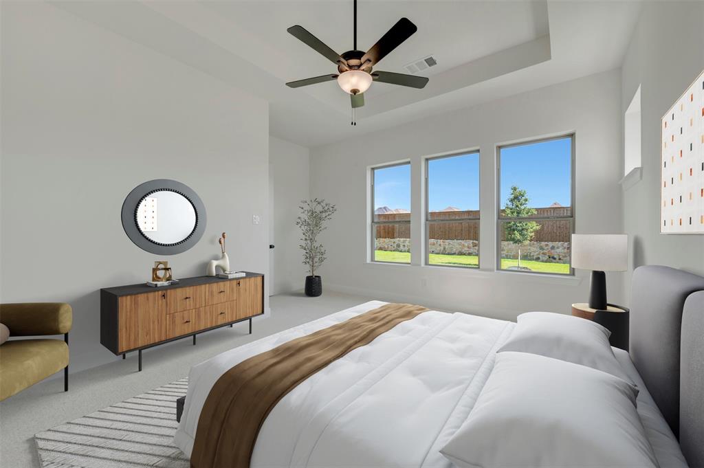 Spacious interior featuring a tray ceiling, ceiling fan with integrated lighting, and three large windows