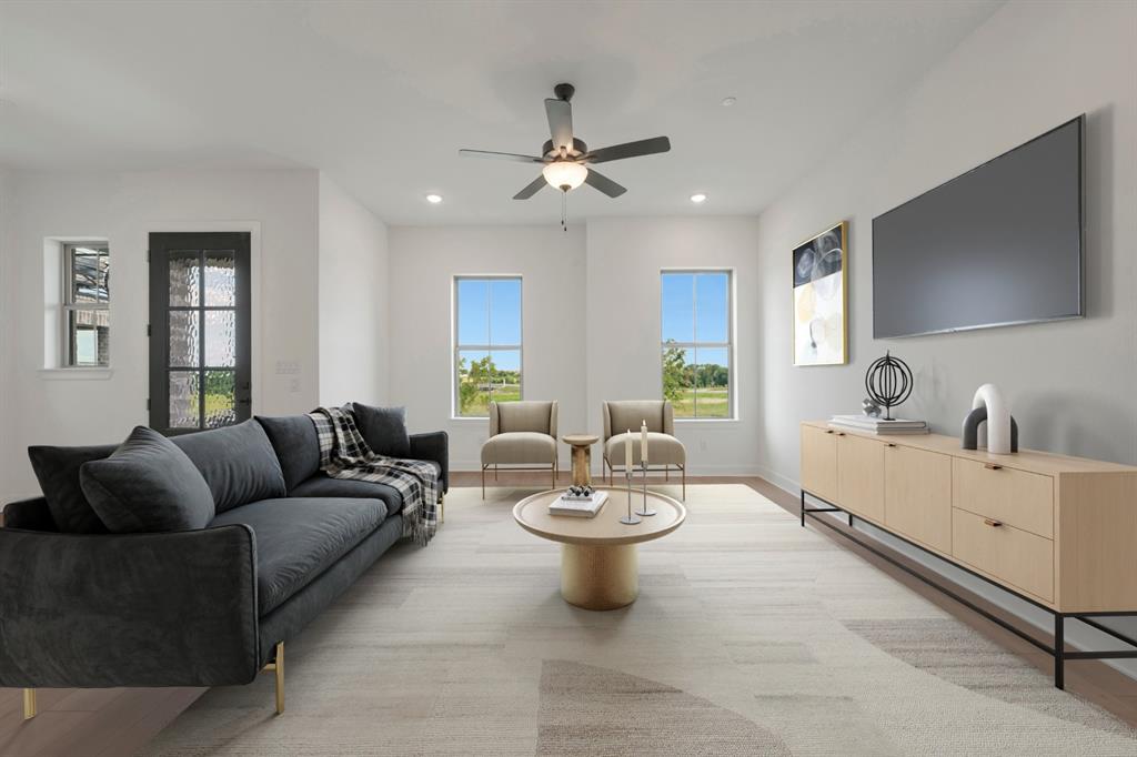 Spacious living area featuring light wood-finish flooring, recessed lighting, and a ceiling fan