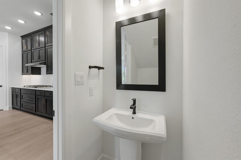 Pedestal sink with matte black faucet, framed mirror, and contemporary light fixture