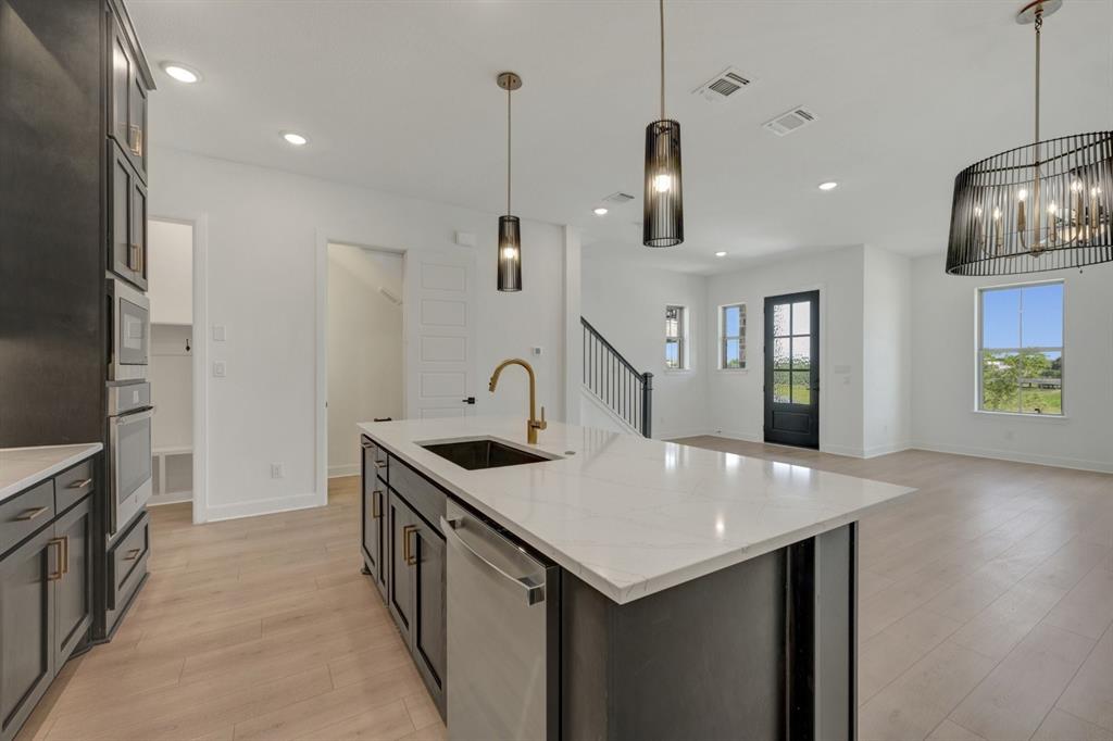 Contemporary kitchen featuring a large island with white stone countertop, integrated sink, and bronze-finish faucet