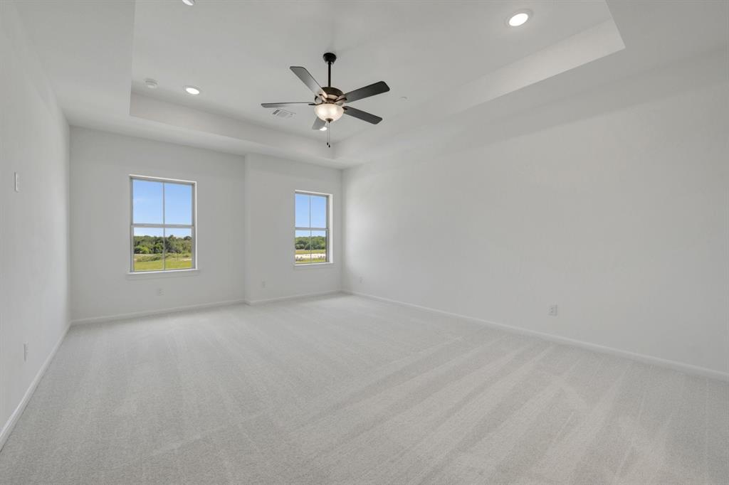 Spacious room featuring light-colored carpeting and white walls