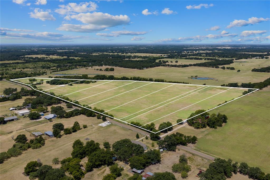Expansive undeveloped land featuring multiple subdivided parcels, surrounding wooded areas, and distant agricultural fields