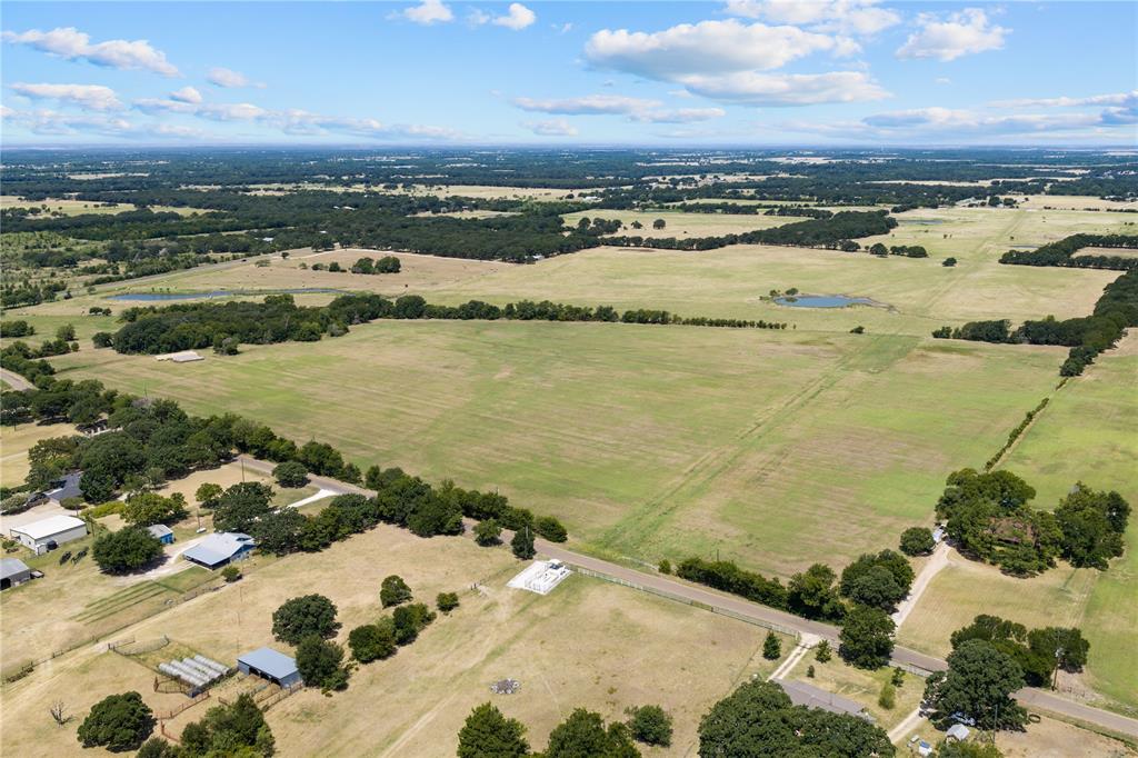 Expansive land featuring agricultural fields, mature trees, a private pond, and multiple structures