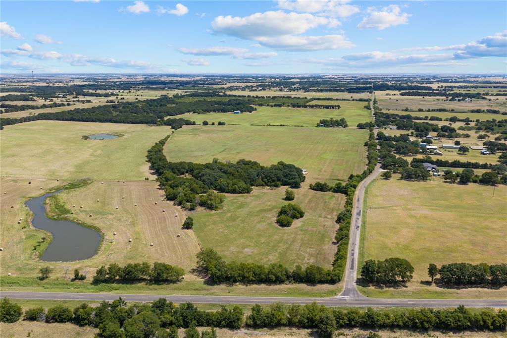 Expansive land parcel featuring a winding roadway, established trees, and two distinct water features Expansive land parcel featuring a winding roadway, established trees, and two distinct water features