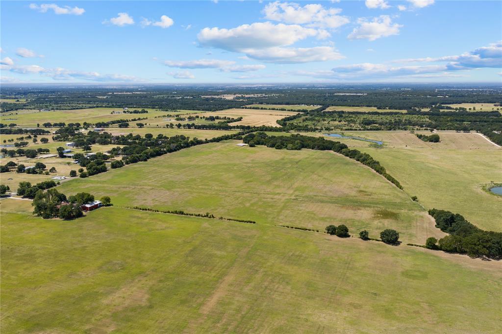 Expansive green acreage with scattered mature trees and distant water features Expansive green acreage with scattered mature trees and distant water features