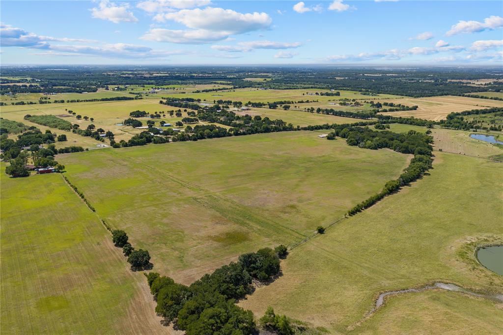 Expansive acreage featuring open fields, scattered mature trees, and a natural pond Expansive acreage featuring open fields, scattered mature trees, and a natural pond