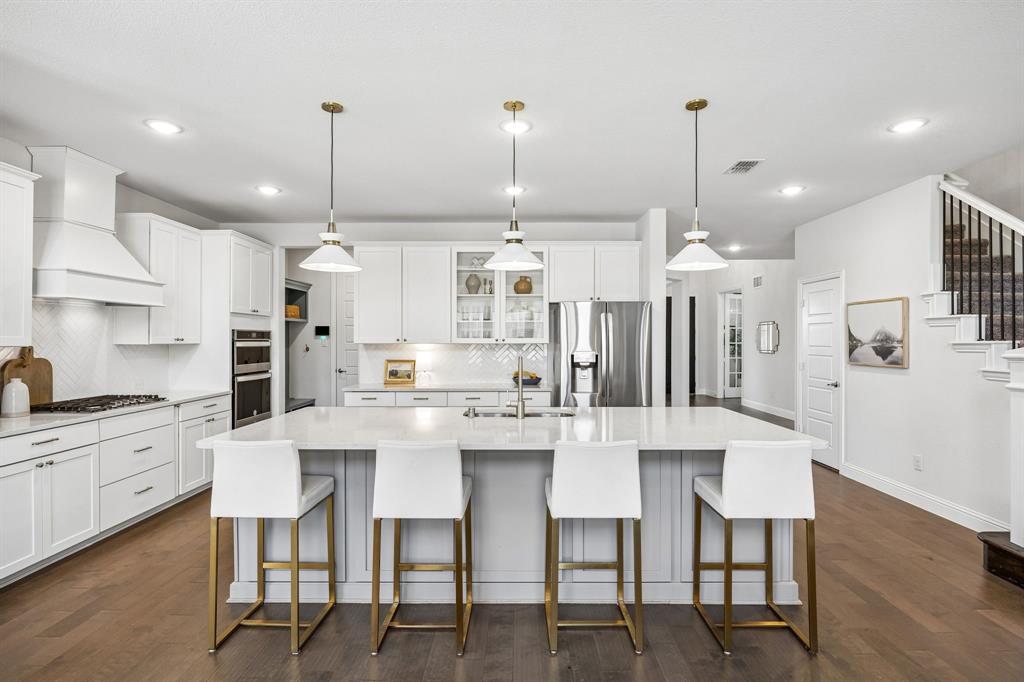 Kitchen featuring glass fronted cabinets, a large island, stainless steel appliances, white cabinets, and dark wood finished floors