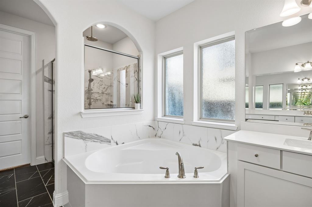 Full bath featuring a marble finish shower, a garden tub, and vanity
