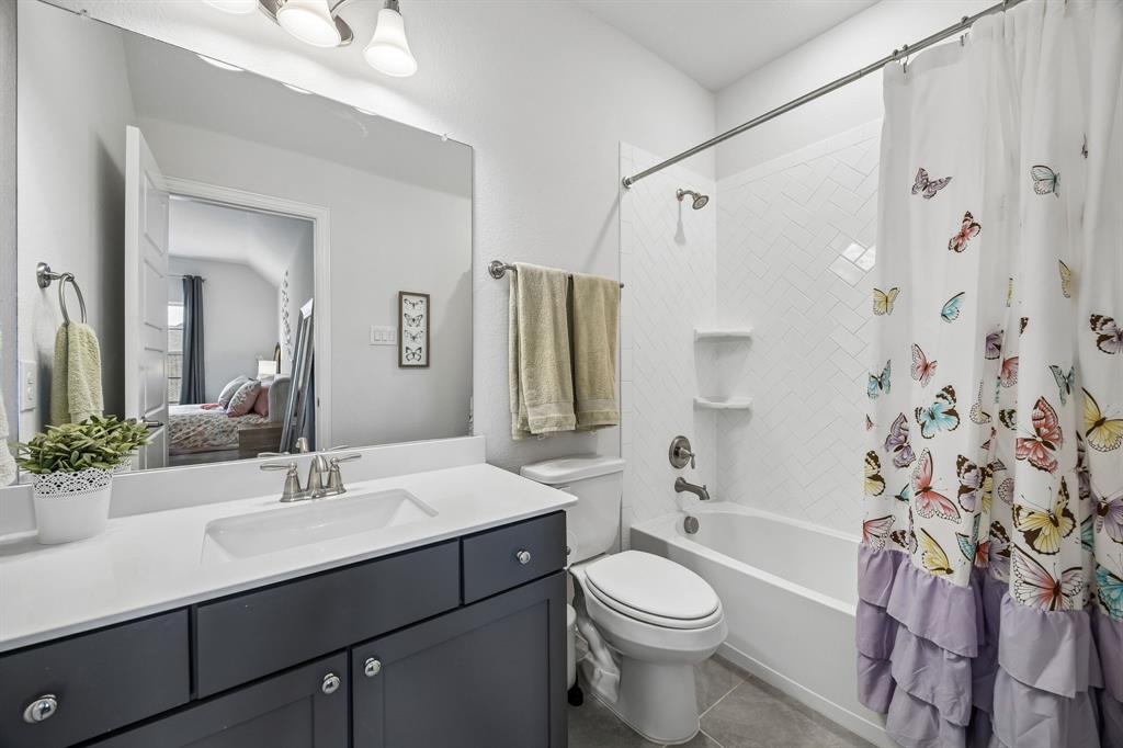 Full bathroom with vanity, shower / bathtub combination with curtain, ensuite bathroom, and dark tile patterned floors