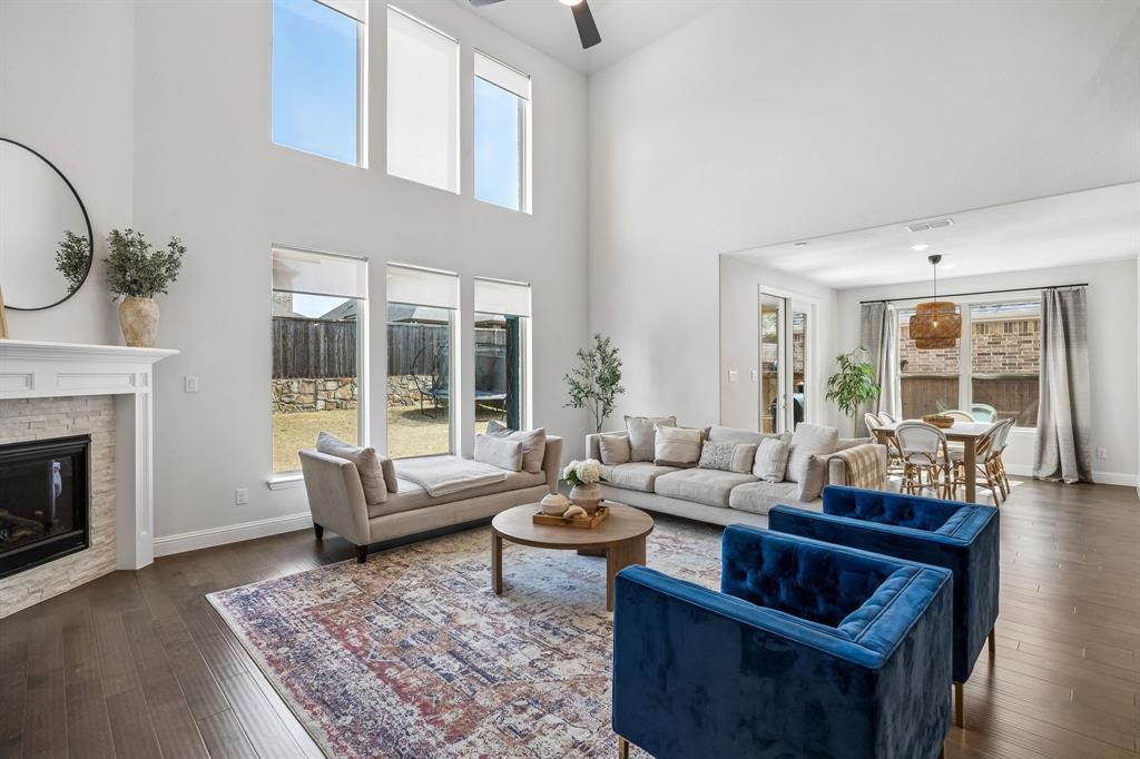 Living area featuring dark wood-style floors, a brick fireplace, a ceiling fan, and a high ceiling