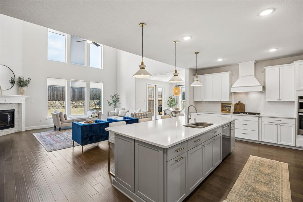 Kitchen with open floor plan, pendant lighting, a kitchen island with sink, decorative backsplash, and two tone cabinetry