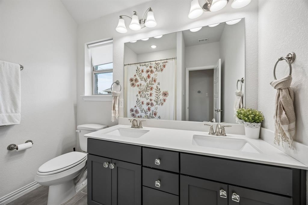 Bathroom with double vanity, a shower with shower curtain, and a textured wall