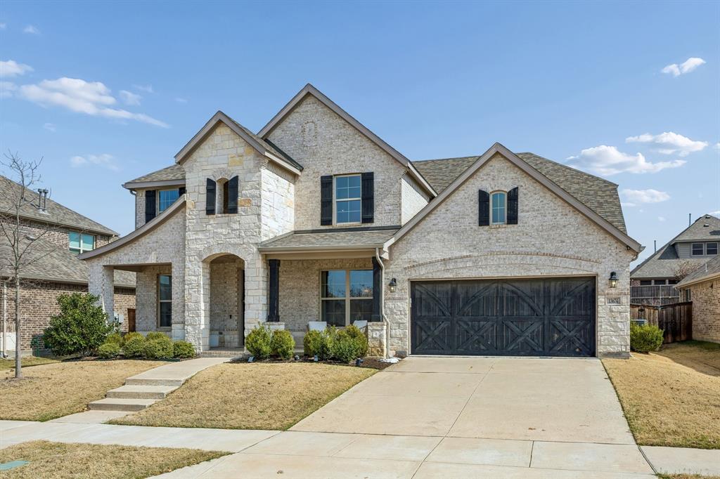 French provincial home with covered porch, concrete driveway, brick siding, stone siding, and roof with shingles
