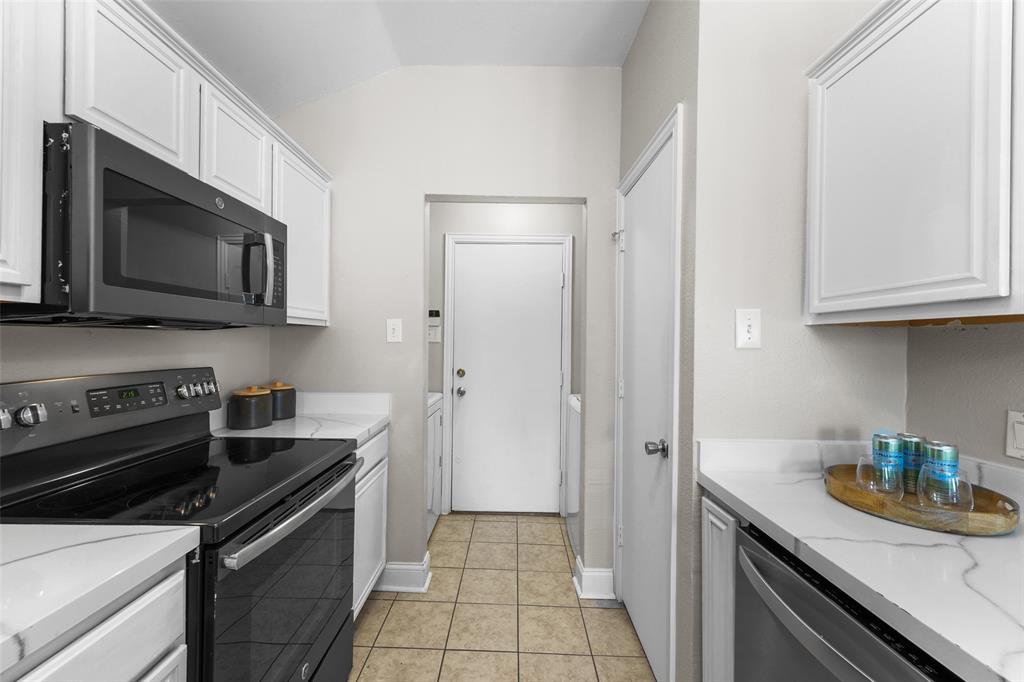 Kitchen featuring black range with electric cooktop, white cabinets, dishwasher, light tile patterned flooring, and lofted ceiling