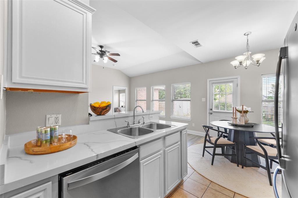 Kitchen featuring stainless steel appliances, white cabinets, hanging lights, ceiling fan, and a peninsula